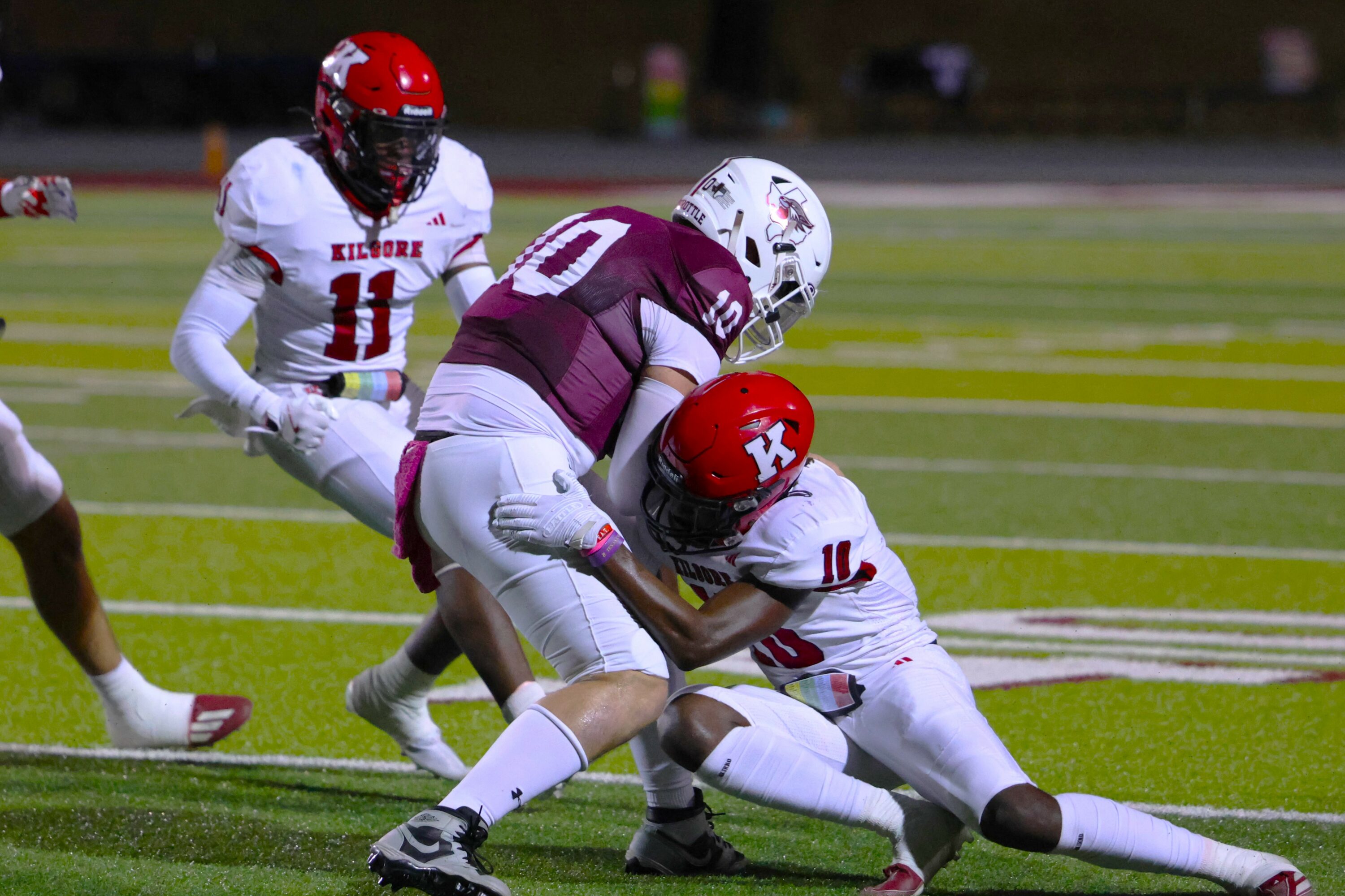 Kilgore's Jamarian Duncan (10) and La'Perrion Graves (11) wrap up Palestine quarterback Rohyn Price. Kilgore was all over Palestine Friday night, to the tune of a 52-7 final. Below: members of the KHS Hi-Steppers in action at Wildcat Stadium at halftime Friday night.